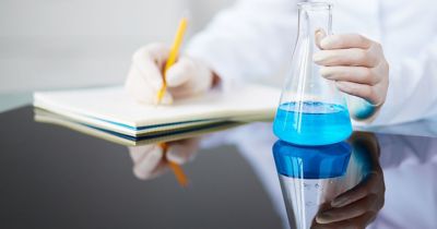 Scientist with a beaker writing on a note pad