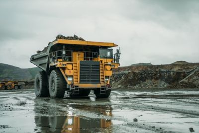 Dump trucks riding on the background of the mine.