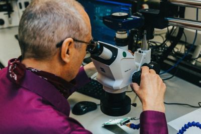 A member of the Ansys Reliability Engineering Services team looking for a failure mechanism under a microscope