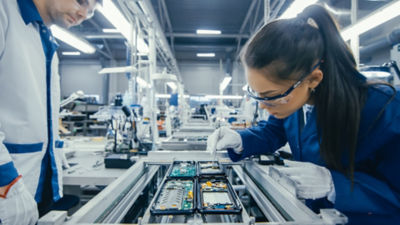 Shot of an Electronics Factory Workers Assembling Circuit Boards by Hand While it Stands on the Assembly Line. High Tech Factory Facility., Shot of an Electronics Factory Workers Assembling Circuit Boards