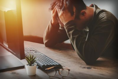 Struggled looking man sitting at a computer desk