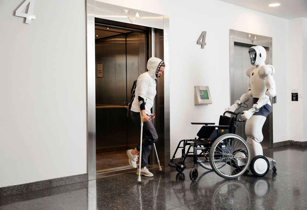 Humanoid robot pushing person in wheelchair