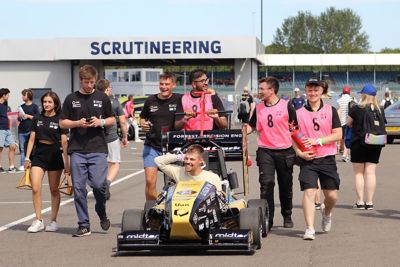 Group of people walking behind a race car